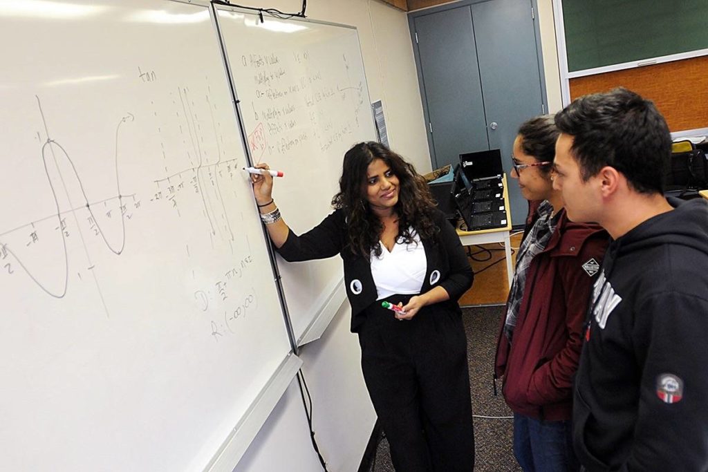 Kohila Sivas teaching at a whiteboard with two students