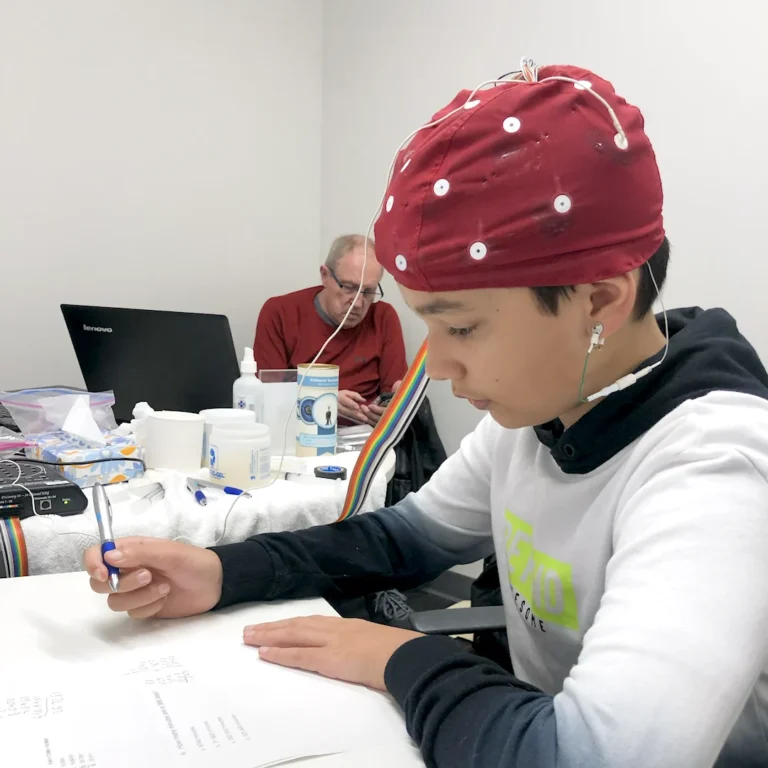 A student in an EEG cap working on a written task